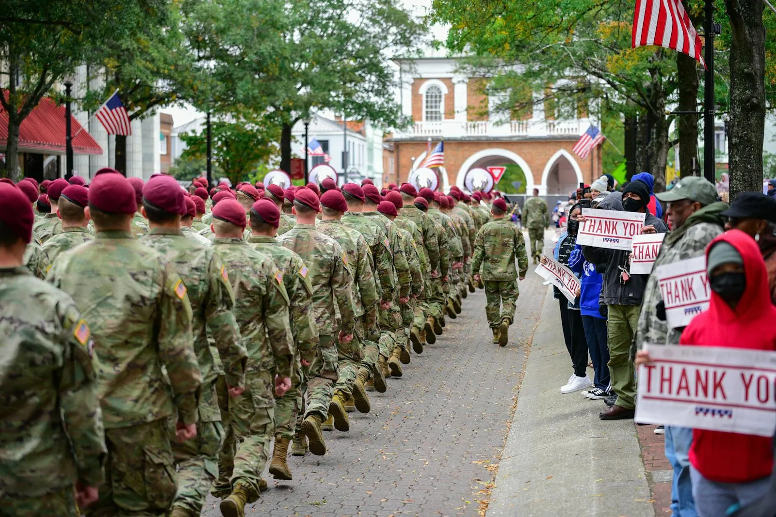 Veterans marching past a crowd of grateful supporters holding thank-you signs