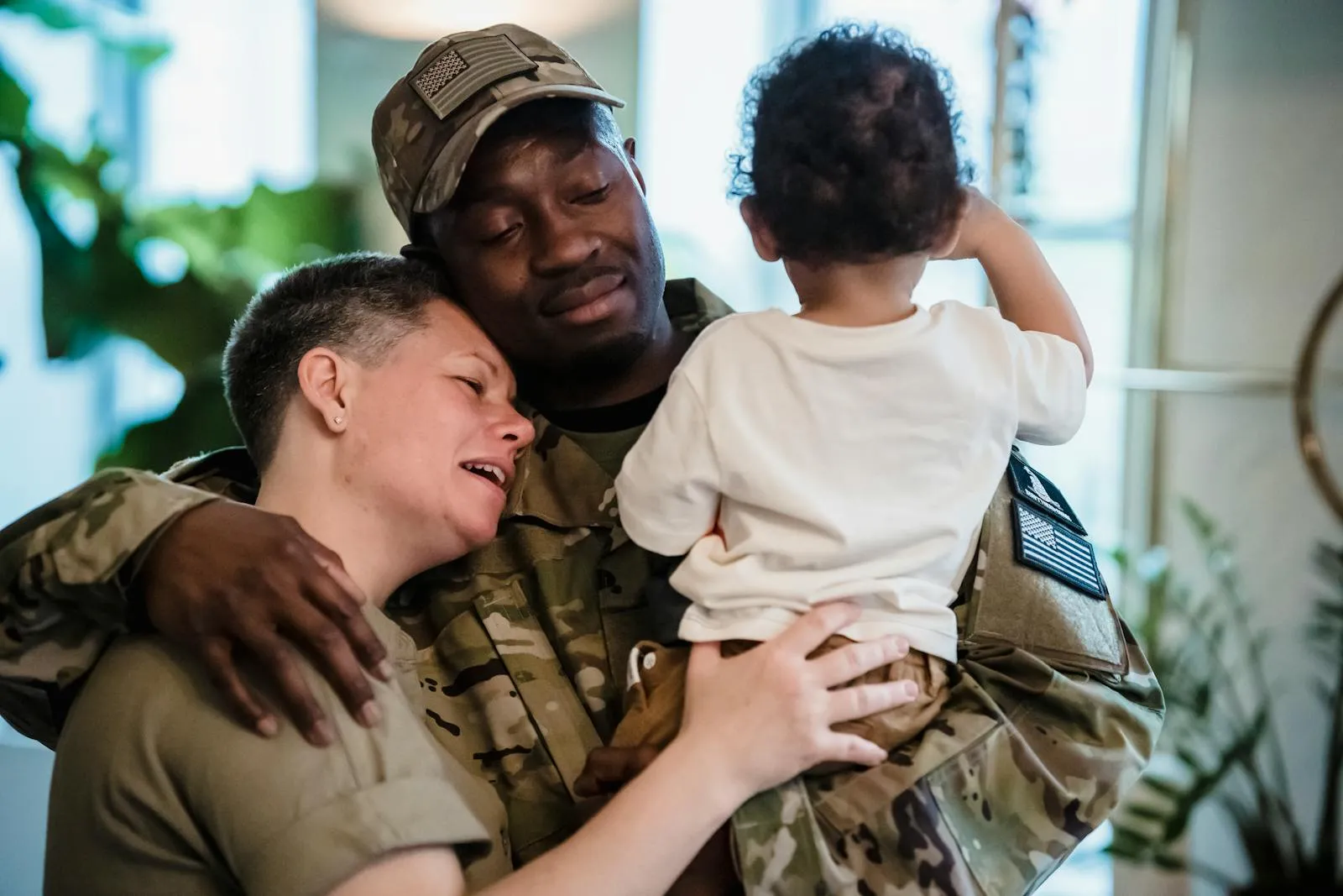 A soldier embraces their spouse and child